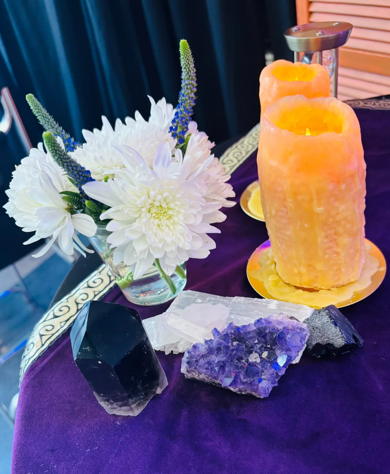 White flowers, crystals, and glowing candles on a purple table