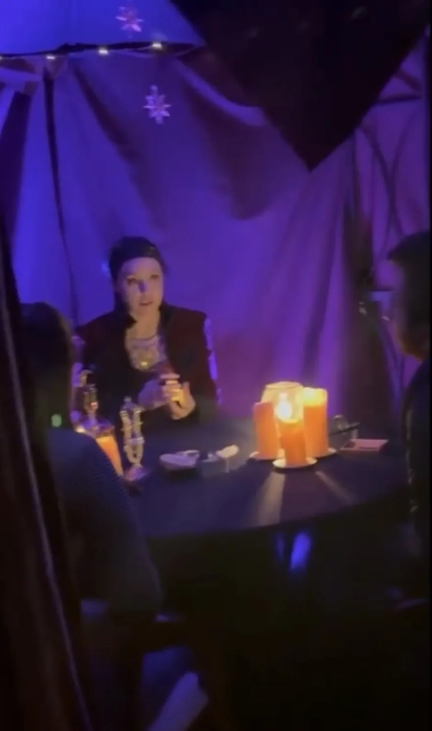 LoriLei reading tarot for guests in a purple-lit space
