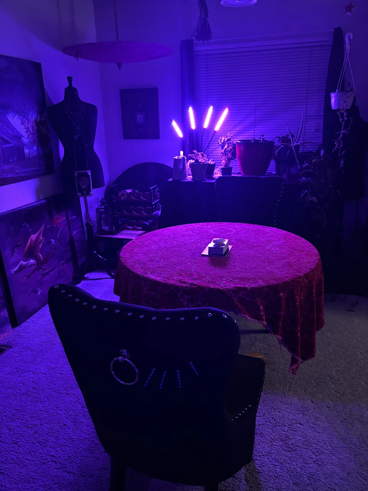A purple-lit reading room with a round velvet-covered table