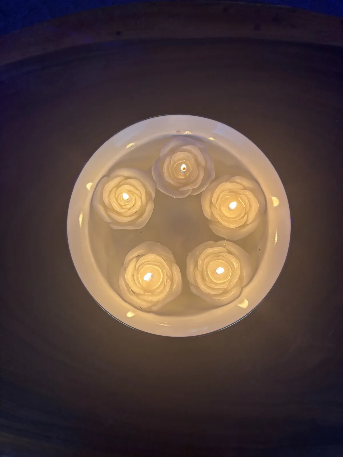Five glowing rose-shaped candles on a white tray
